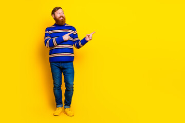 Naklejka premium Cheerful young red haired man in a vibrant outfit gesturing confidently on a yellow background for casual advertising