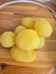 Boiled peeled potatoes in a glass bowl on a wooden table 