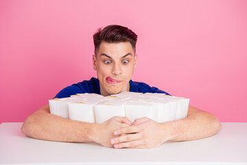 Young man with energetic expression surrounded by stylish packaging boxes against a vibrant pink background