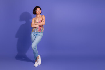 Stylish young woman in vibrant outfit standing confidently against purple backdrop, embodying...