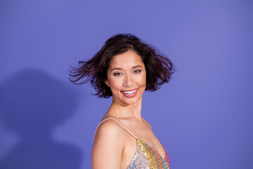 Young woman wearing a colorful sequined top, smiling confidently, with purple background,...