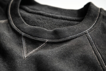 Close-up of black sweatshirt fabric and stitching details, soft fleece texture and seam design in minimalist casual clothing
