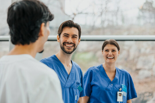 Happy male medical professional spending leisure time with coworkers in hospital