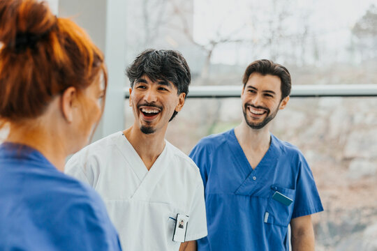 Happy male healthcare experts spending leisure time with female colleague at hospital