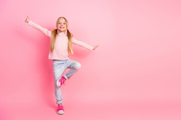 Adorable young girl posing cheerfully in pink background with stylish outfit and playful expression, showcasing childhood joy and fashion
