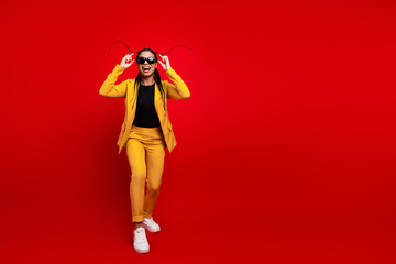 Confident young businesswoman in vibrant yellow suit posing with playful expression against bright...