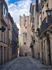 Fototapeta premium Clavero Tower and Old Salamanca Street: Narrow street leading to the Clavero Tower in Salamanca, Spain, showcasing a mix of historical and traditional architecture.