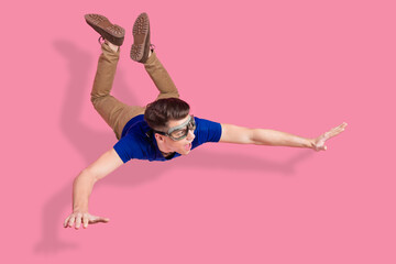 Funny man in goggles mimicking freefall against pink background showcasing energy, adventure, and...