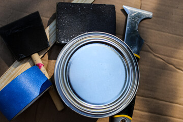materials for painting. a can, sanding block, blue tape, sponge brush, multi-use tool, and mixing...