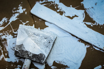 close-up view of a white paint splattered surface with a stir stick and foam brush. home...