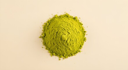 A small pile of bright green matcha powder rests on a plain cream background under soft studio lighting.