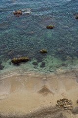 Clear sea water with rocks and gentle waves on sandy beach