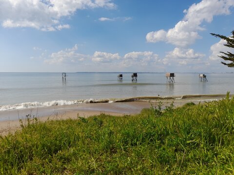 P&ecirc;cheries et houle &agrave; Tharon Plage sous un ciel bleu parsem&eacute; de nuages