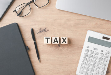Tax and Accounting Concept.Wooden blocks spelling TAX on wooden desk with calculator, notebook,...