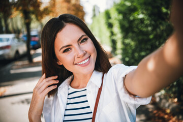 Delighted young woman enjoying a sunny urban stroll in stylish casual wear