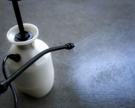 looking down at a pump sprayer being used to apply clear concrete sealer. home improvement background with copy space