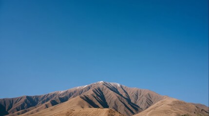 Fototapeta premium Majestic mountain range with rugged ridges transitions from light brown at the base to deep brown at the peaks,