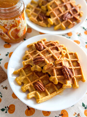 Autumn breakfast with pumpkin waffles, pecans and a jar of orange jam