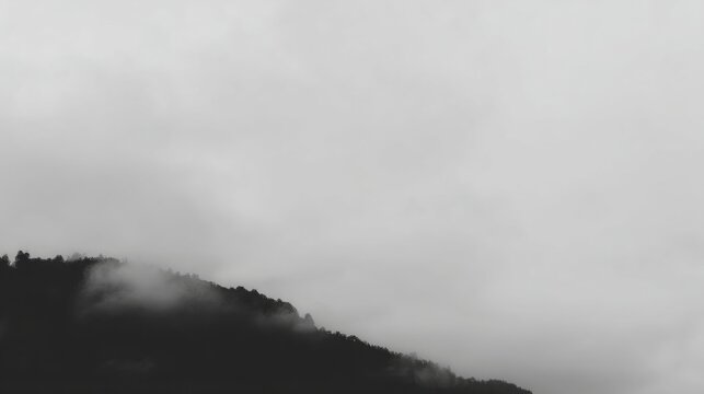 Serene grayscale landscape dominated by a mountain under an overcast sky with dense clouds creating a moody contemplativ