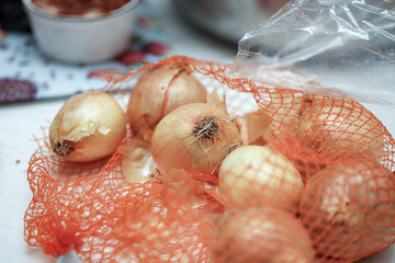 Onions in orange netting ready for preparation in a kitchen setting with a blurred background