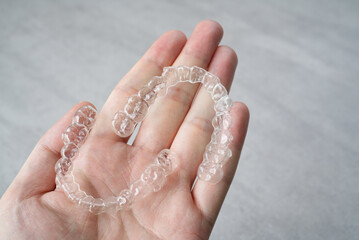 Clear dental aligner in hand. Orthodontic mouthpiece display.