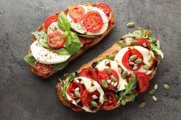 Delicious sandwiches with mozzarella cheese and tomatoes on grey table, flat lay