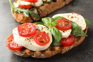 Delicious sandwiches with mozzarella cheese and tomatoes on grey table, closeup