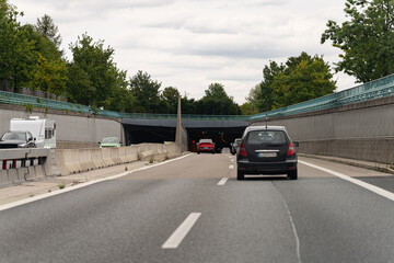 Roadway leading into tunnel with vehicles travelling on highway during cloudy day