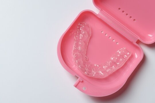 One clear aligner and retainer case on light grey background, top view. Space for text