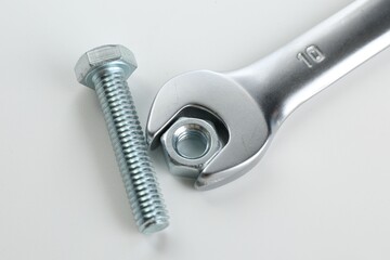 Metal wrench, bolt and nut on white background, closeup