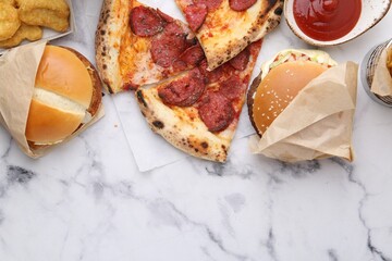Different delicious fast food on white marble table, flat lay. Space for text