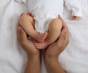 Father with his cute newborn baby on bed, top view