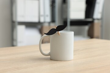 Happy Father's Day. Cup with paper moustache on wooden table