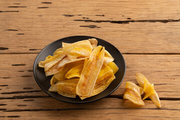 Crispy fried sliced banana with salt,salty taste banana chips in black plate.
