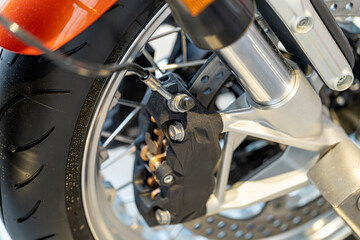Obraz premium Close-up view of a motorcycle brake system showcasing details of a caliper and tire in a modern garage setting