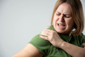 Close-up of woman with shoulder pain, feeling discomfort and ache from injury or strain on isolated...