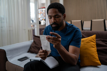 Worried African man under stress thinking about finances, burdened by living costs, loans, and inflation, financial anxiety.