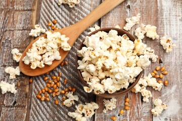 Tasty popcorn and corn kernels on wooden table, flat lay
