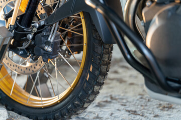 Motorcycle close-up showcasing tire, rim, and intricate details in a garage setting during daylight