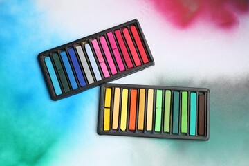 Colorful chalk pastels in trays on color background, flat lay