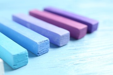 Colorful chalk pastels on light wooden table, closeup