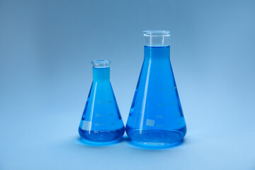 Flasks with bright liquid on light blue gradient background