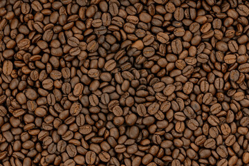 Roasted coffee beans background. A brown food texture or pattern of aromatic arabica for a cafe. Top view of caffeinated espresso wallpaper.