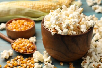 Tasty popcorn and corn kernels on blue wooden table, closeup