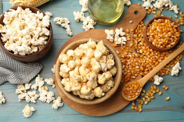 Tasty popcorn and corn kernels on blue wooden table, flat lay