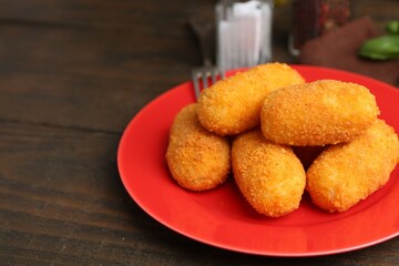 Many delicious fried croquettes on wooden table, closeup