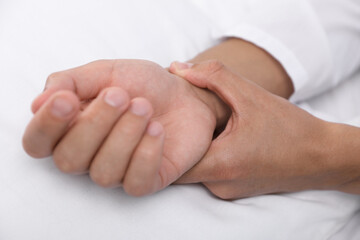 Man checking his pulse with fingers on bed, closeup
