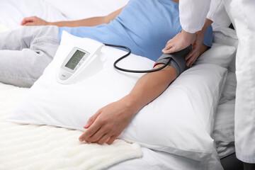 Doctor checking man's heart rate and blood pressure via sphygmomanometer at home, closeup
