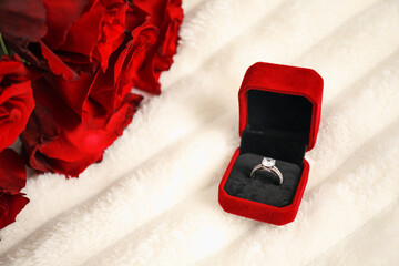 Dreams come true. Beautiful engagement ring in box and flowers on light plaid, closeup