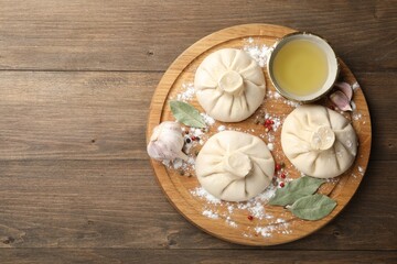 Uncooked khinkalis (dumplings) with peppercorns, flour and bay leaves on wooden table, top view. Space for text